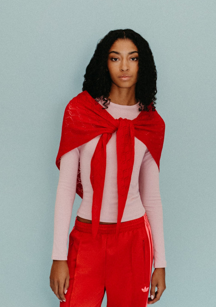 Model wearing TBCo Large Merino Wool Triangle Scarf in Red Pointelle tied loosely over a pale pink top
