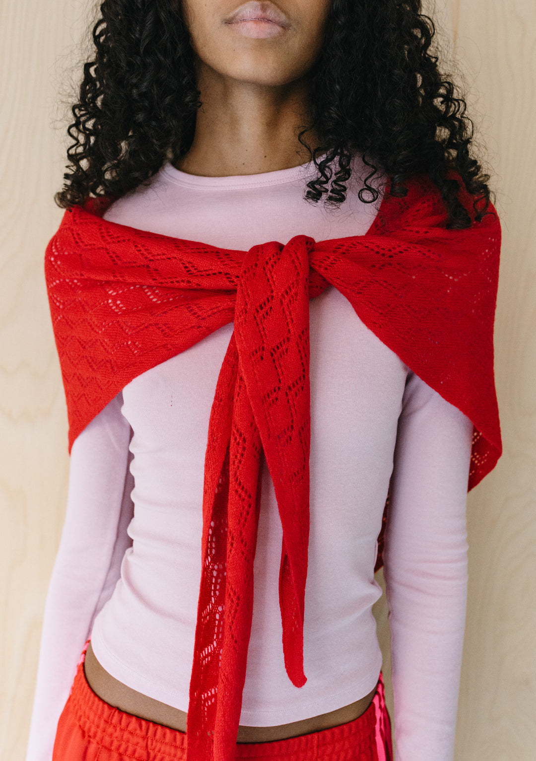 Front view of model wearing TBCo Large Merino Wool Triangle Scarf in Red Pointelle with delicate knitted pattern