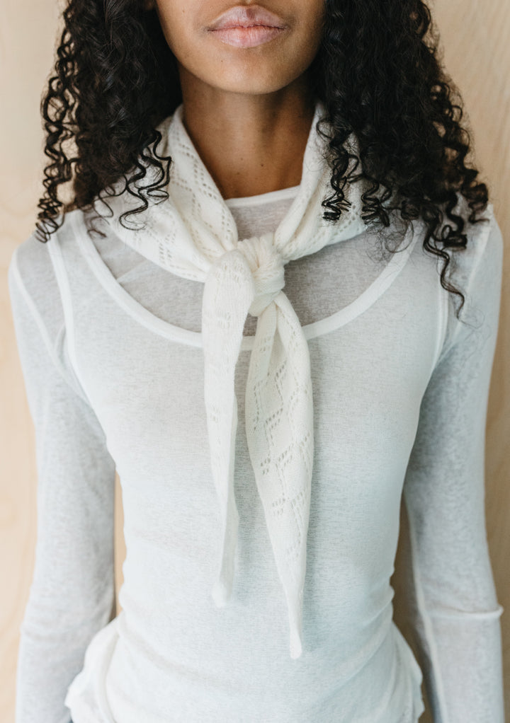 Close-up of model wearing TBCo Merino Wool Triangle Scarf in White Pointelle tied at the neck over white top