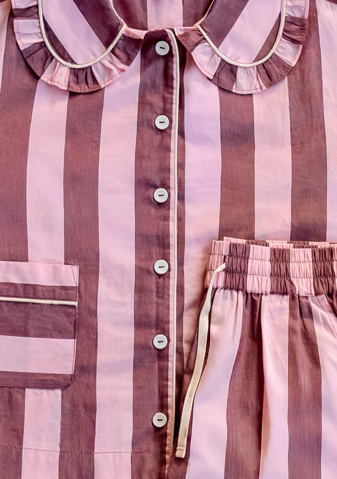 Close-up of TBCo Cropped Cotton Pyjamas in Pink & Burgundy Stripe showing button front, ruffled collar, and drawstring waist detail