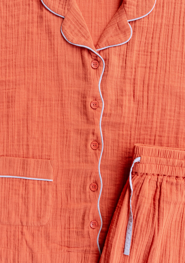 Close-up of TBCo Cotton Pyjamas in Rust showing soft textured cotton with lilac contrast piping and button details