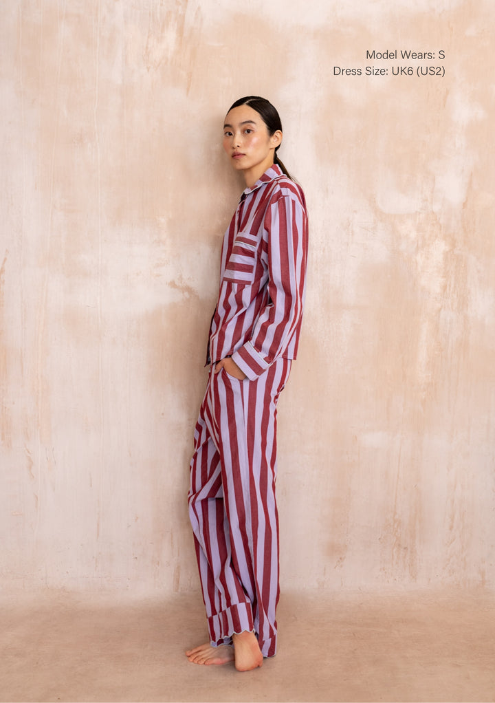Model in a TBCo Cotton Pyjamas in Lilac Stripe with scalloped collar, relaxed fit, showcasing modern sleepwear style against a textured wall.
