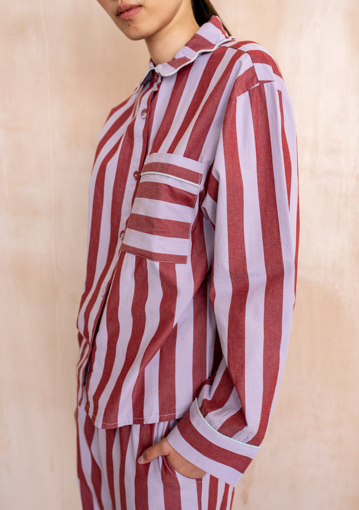 Model in a TBCo Cotton Pyjamas in Lilac Stripe with scalloped collar, relaxed fit, showcasing modern sleepwear style against a textured wall.