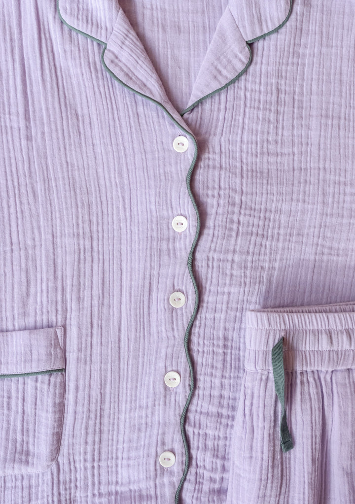 Close-up portrait of TBCo Cotton Pyjamas in Lilac showing green piping and buttons in gallery position 6.