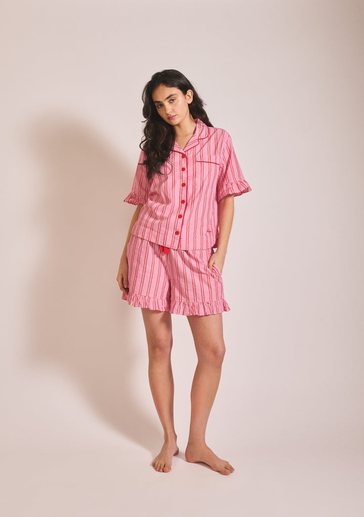 Woman wearing TBCo Cotton Pyjamas in Red Stripe Ruffle standing against plain background portrait orientation gallery 1