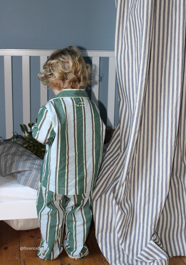Child standing by bed wearing TBCo Cotton Kids Pyjamas in Blue Stripe with relaxed fit and breathable fabric detail