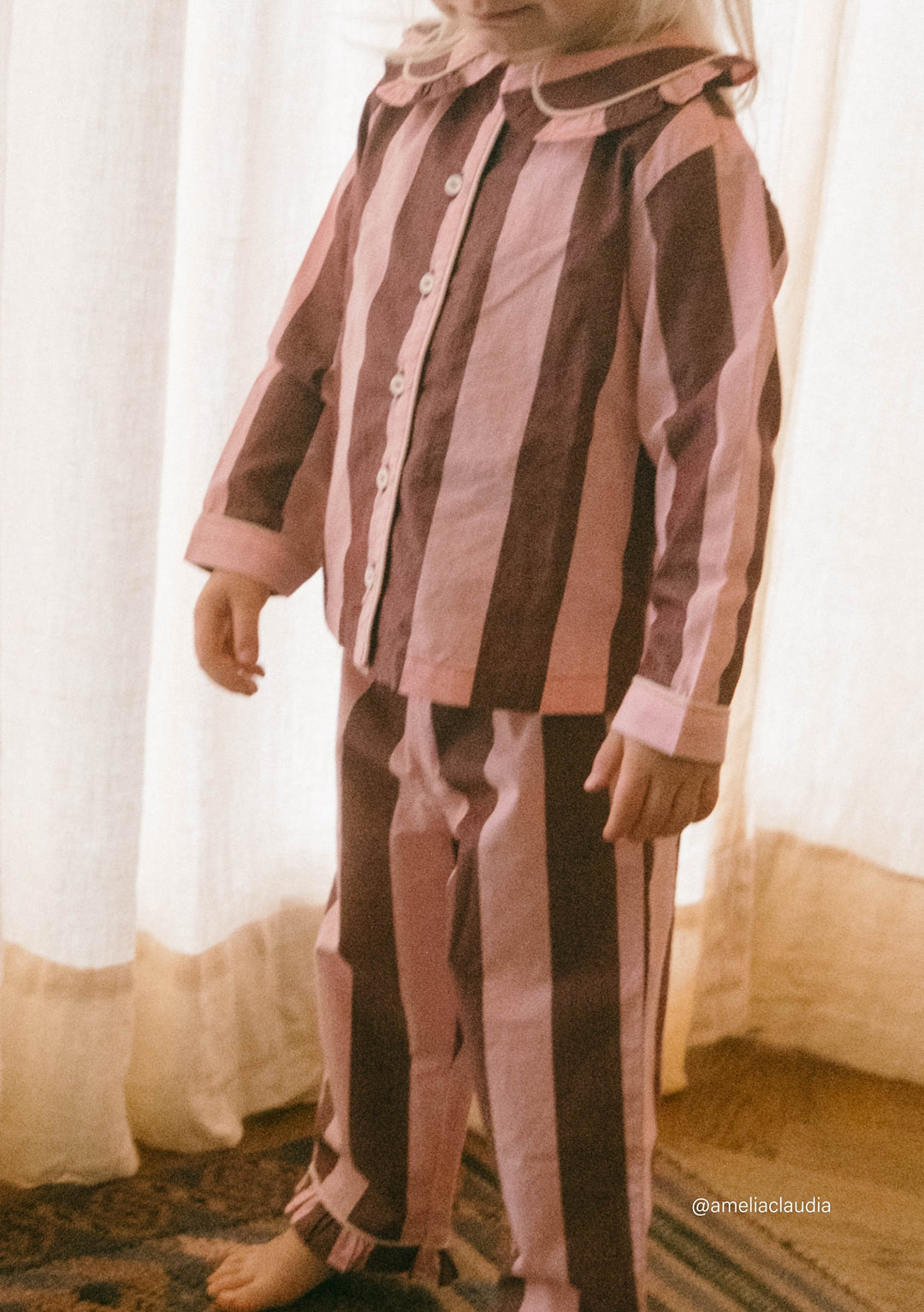 Child wearing TBCo Cotton Kids Pyjamas in Pink & Burgundy Stripe with button-up top and soft breathable fabric details