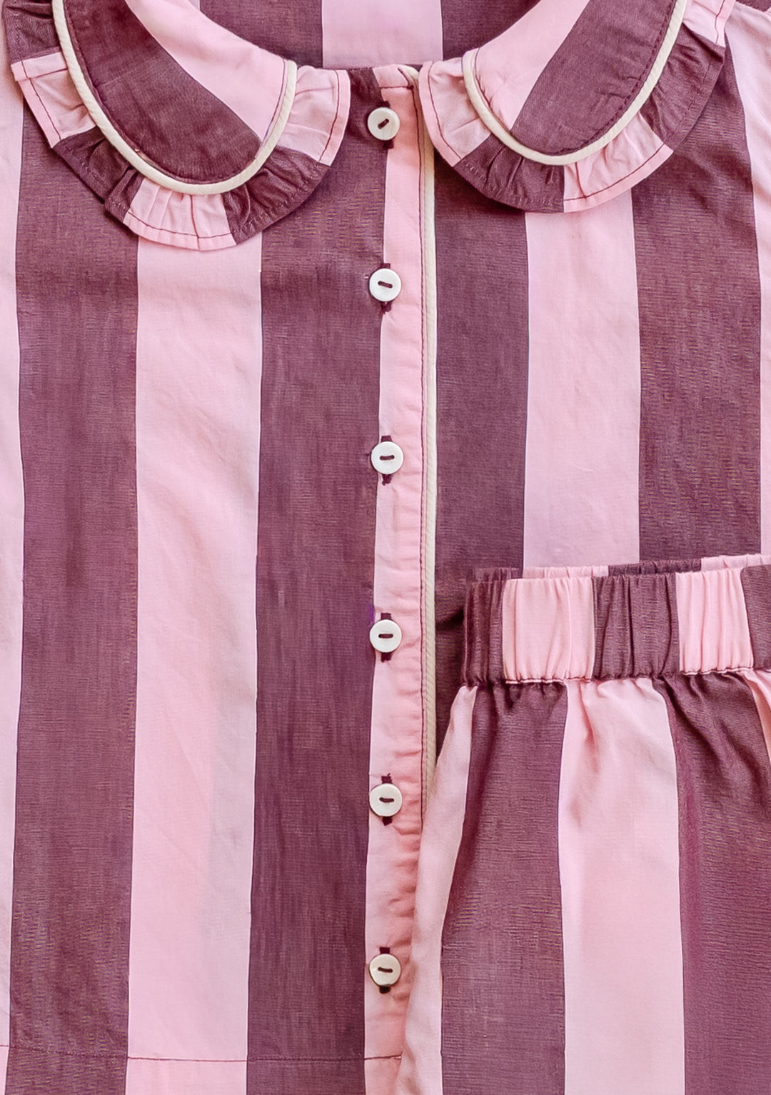Close-up of TBCo Cotton Kids Pyjamas in Pink & Burgundy Stripe showing button front and ruffled collar detail