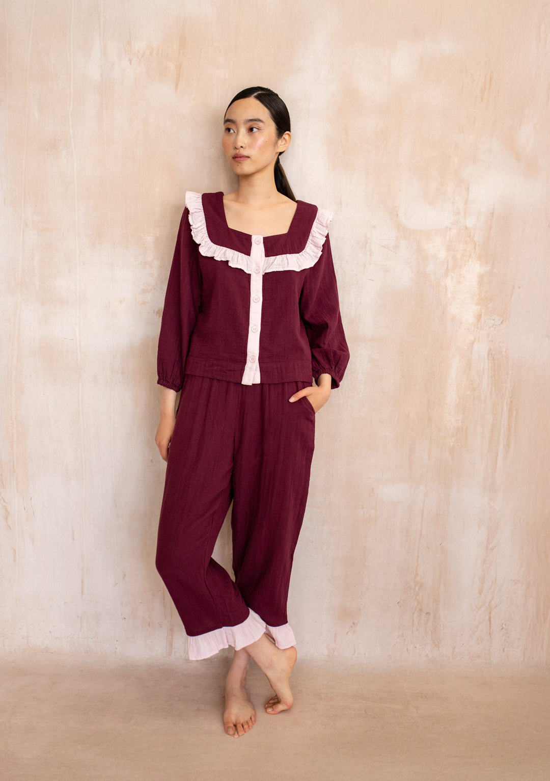 Model wearing TBCo Cotton Pyjamas in Burgundy Ruffle with pink trim, featuring cropped trousers and pockets