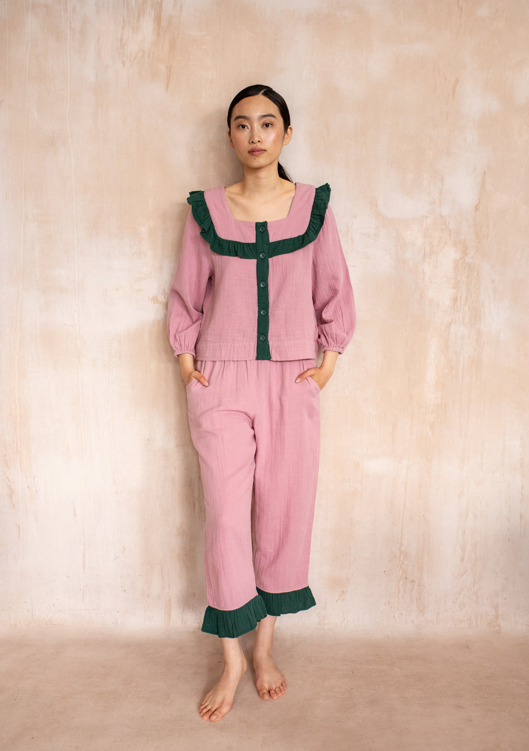 Model wearing TBCo Cotton Pyjamas in Pink Ruffle with green trim, featuring cropped trousers and pockets