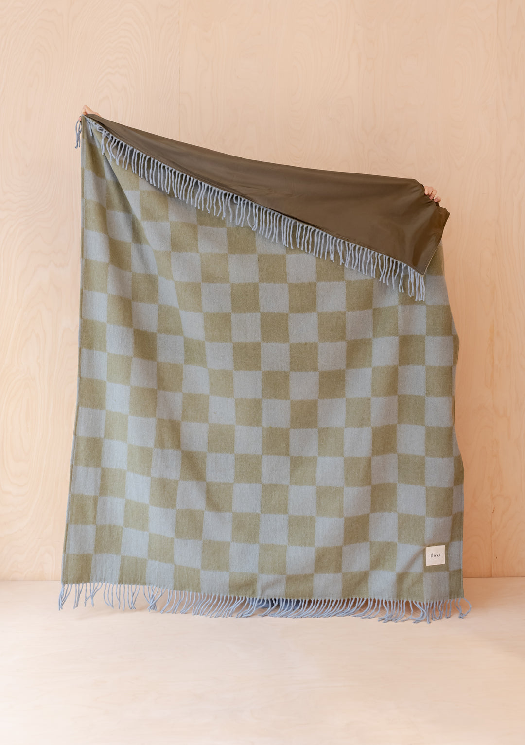 Portrait view of TBCo Recycled Wool Picnic Blanket in Green & Blue Checkerboard showing fringe and reversible side details