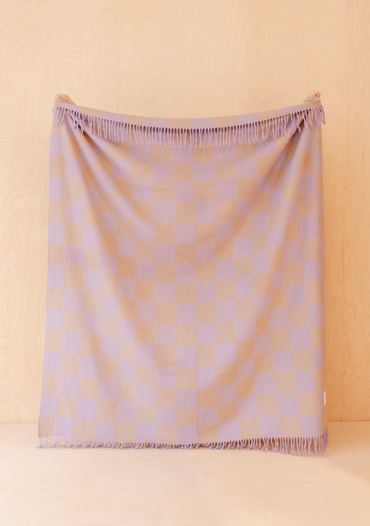 TBCo Recycled Wool Blanket in Lilac & Coffee Checkerboard hanging against light wood with delicate fringed edges visible