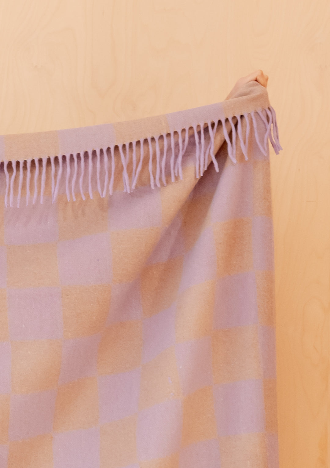 Recycled Wool Blanket in Lilac & Coffee Checkerboard by TBCo hanging, showing fringed edge, portrait gallery shot 4
