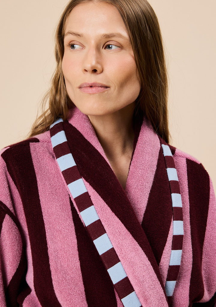 Close-up of model wearing TBCo Terry Cotton Bath Robe in Burgundy Stripe featuring wide vertical stripes and contrast trim