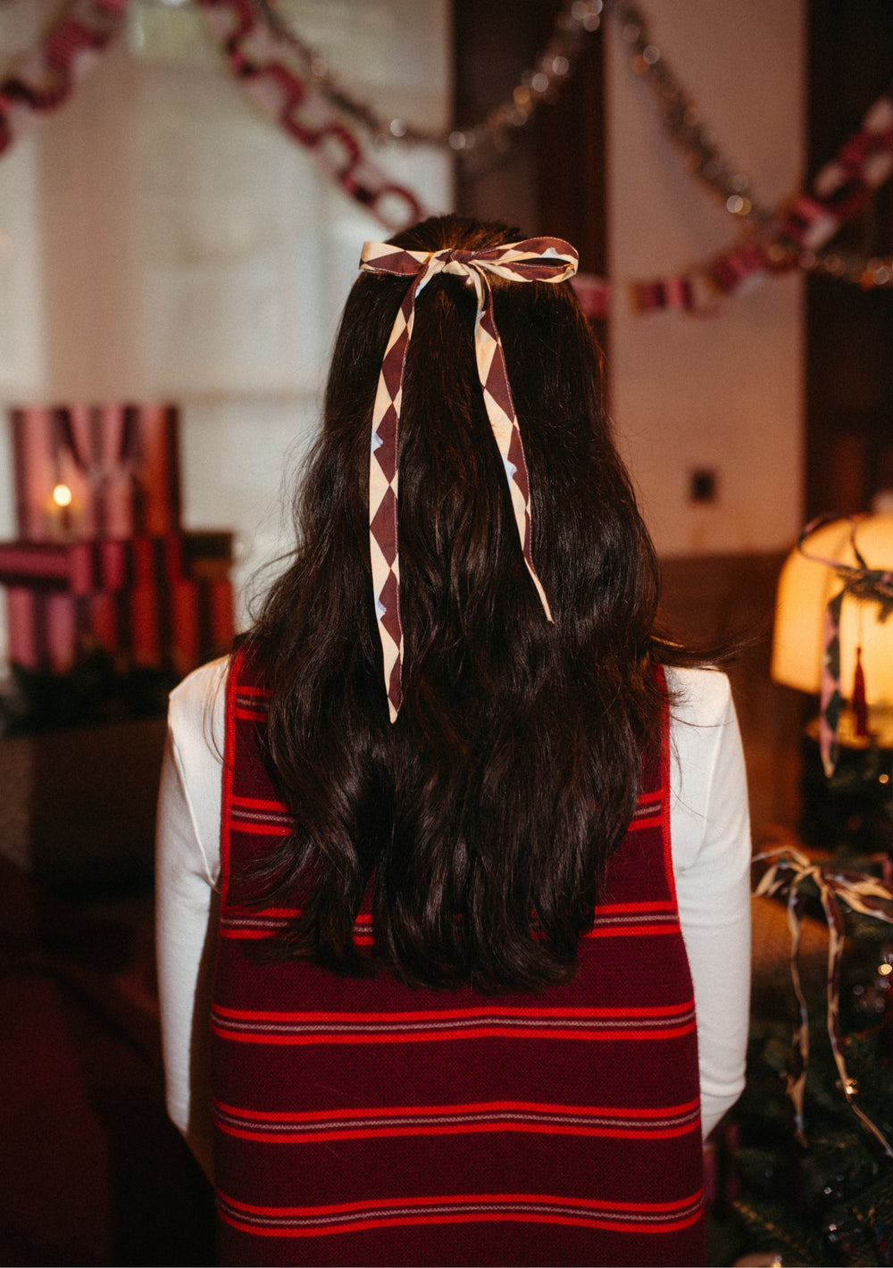 Woman wearing TBCo Cotton Bows, Set of 8 in harlequin design styled in her dark hair with festive background