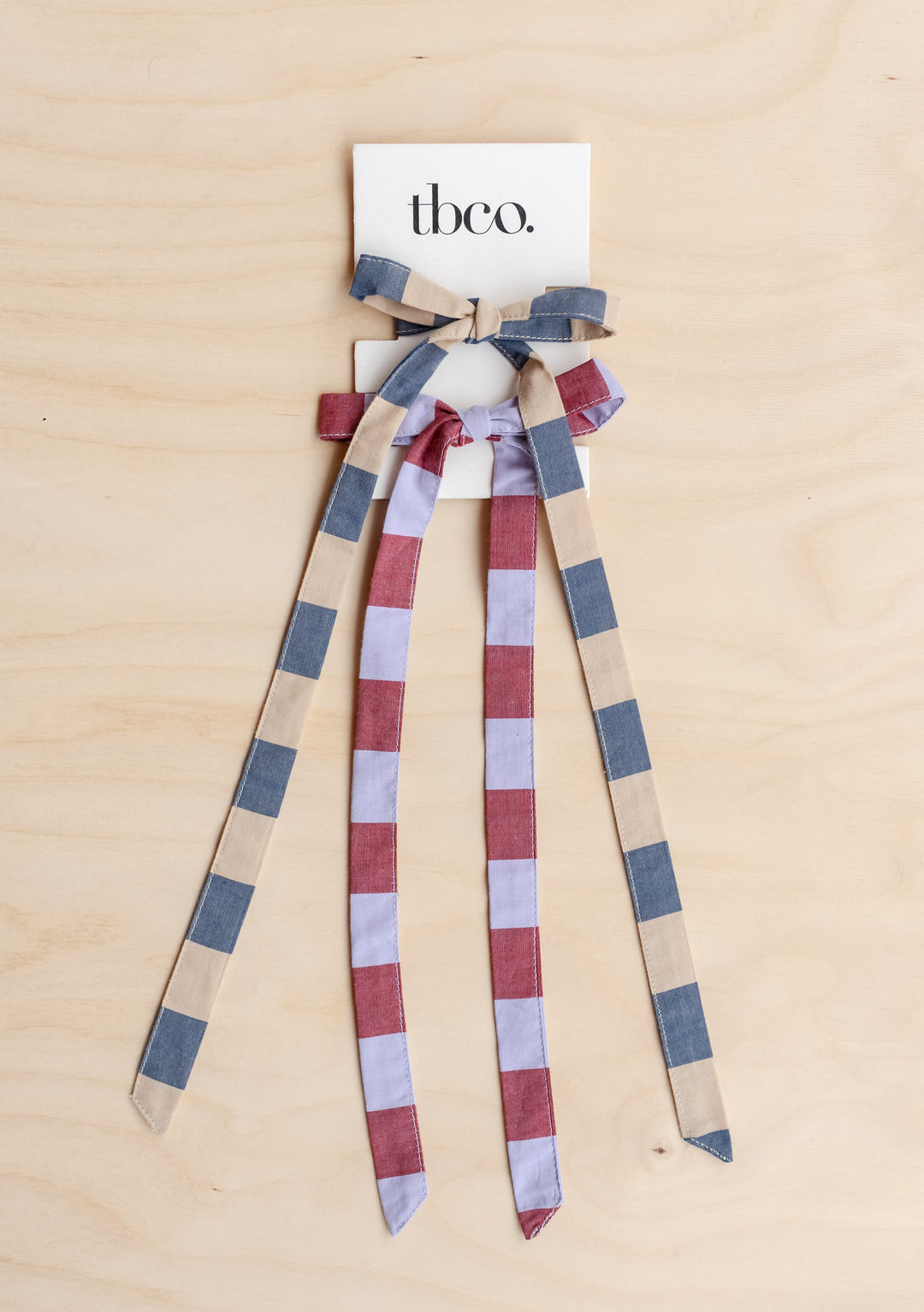 Cotton Bows, Set of 2 in Bold Stripe by TBCo, featuring playful striped cotton ribbons in blue and red tones on wooden background