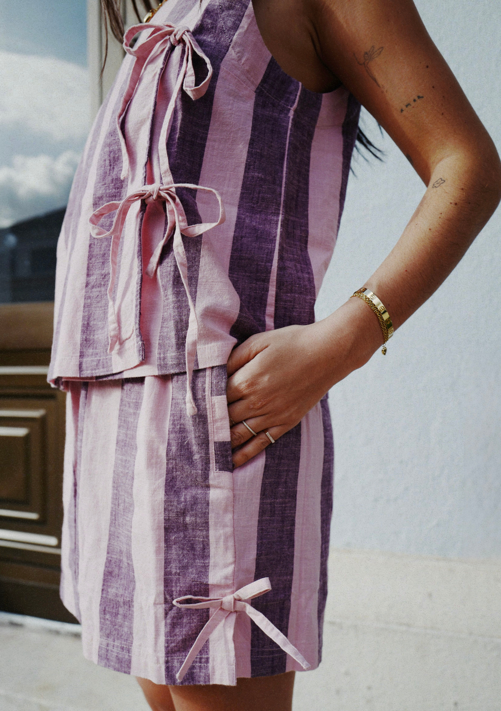 Close-up of TBCo Cotton Tie Shorts in Pink & Burgundy Stripe with side bows and vertical stripes worn outdoors