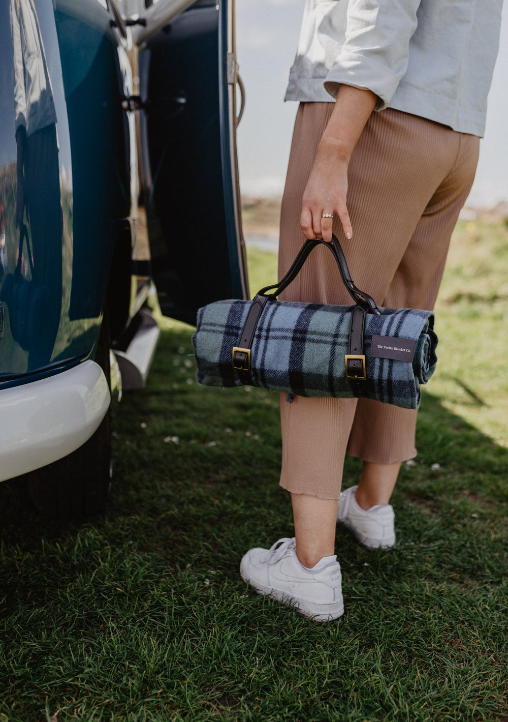 TBCo wool picnic blankets with carrier and should strap arranged in a scenic outdoor setting, showcasing their soft texture and vibrant patterns. Perfect for alfresco dining, relaxing in nature, or stylish outdoor gatherings.